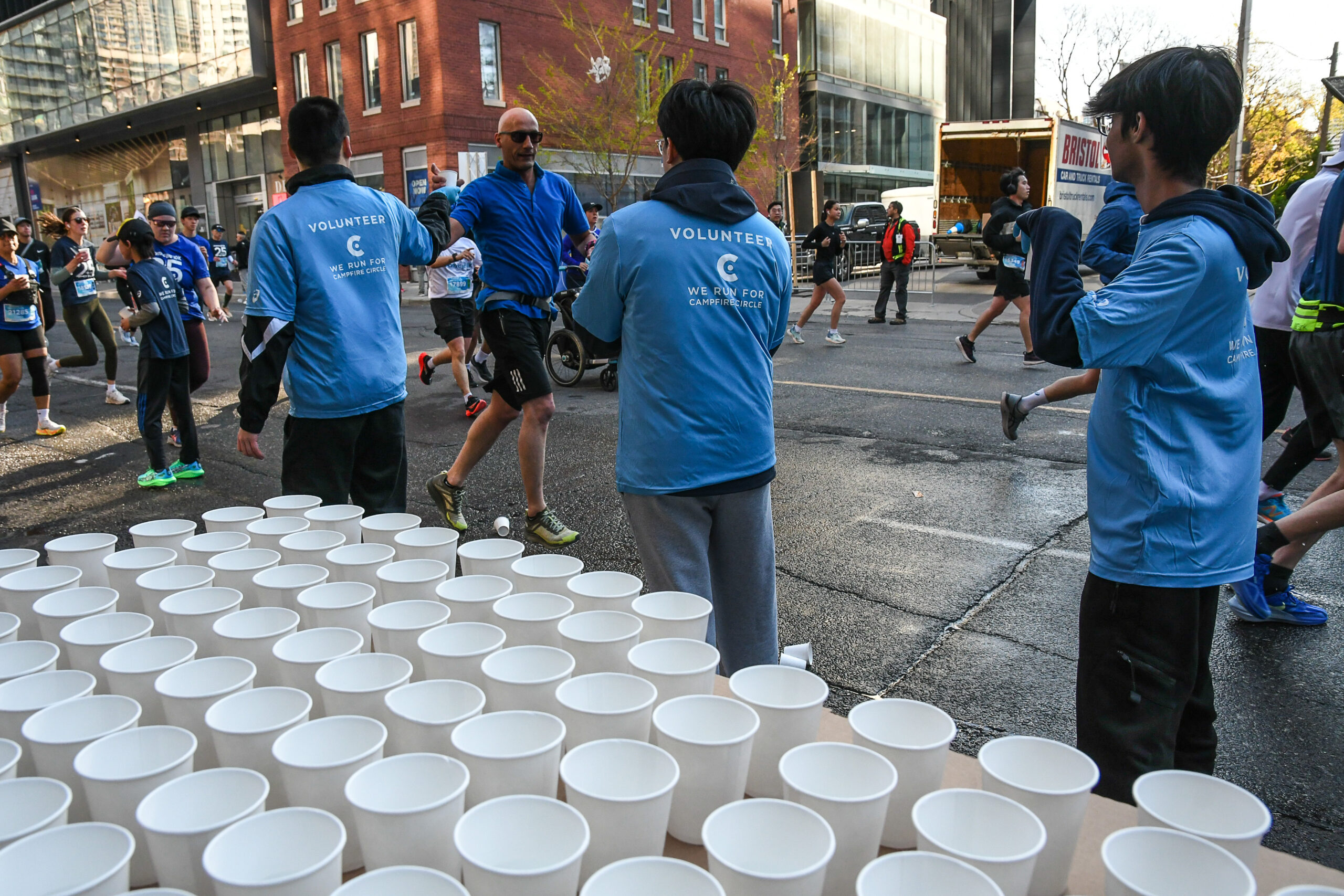 Volunteers hand out water cups to runners during a road race