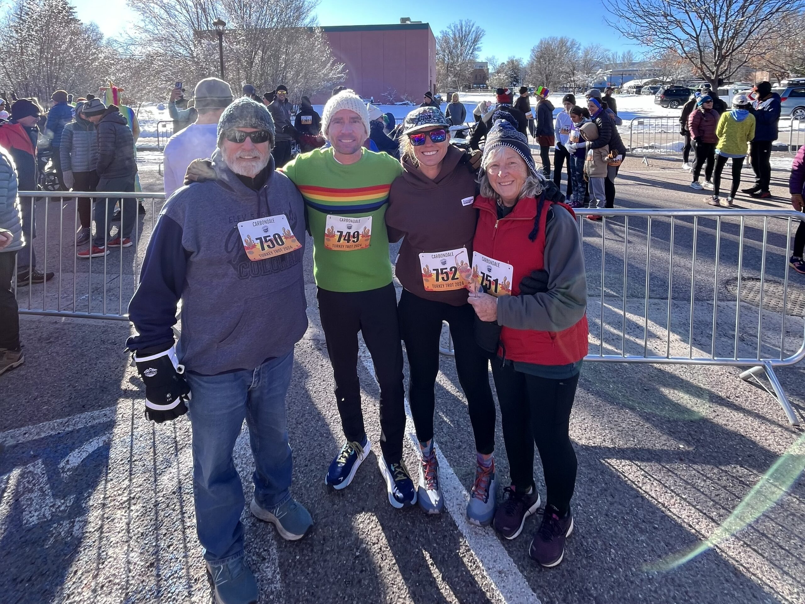 Four smiling family members pose together after completing a local Turkey Trot on a crisp Thanksgiving morning.