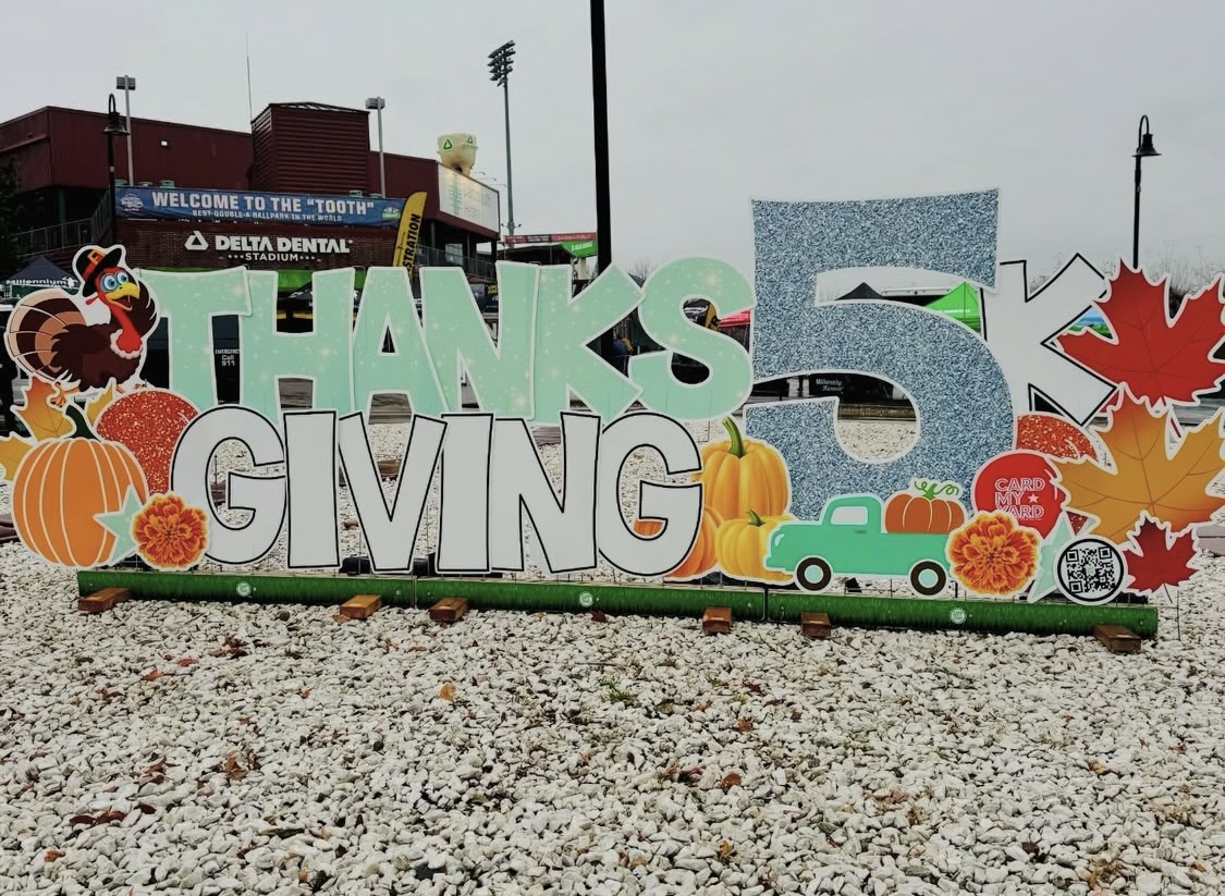 Thanksgiving 5k race sign surrounded by pumpkins and fall decorations at the Dartmouth Health Fisher Cats Thanksgiving 5k in Manchester, New Hampshire