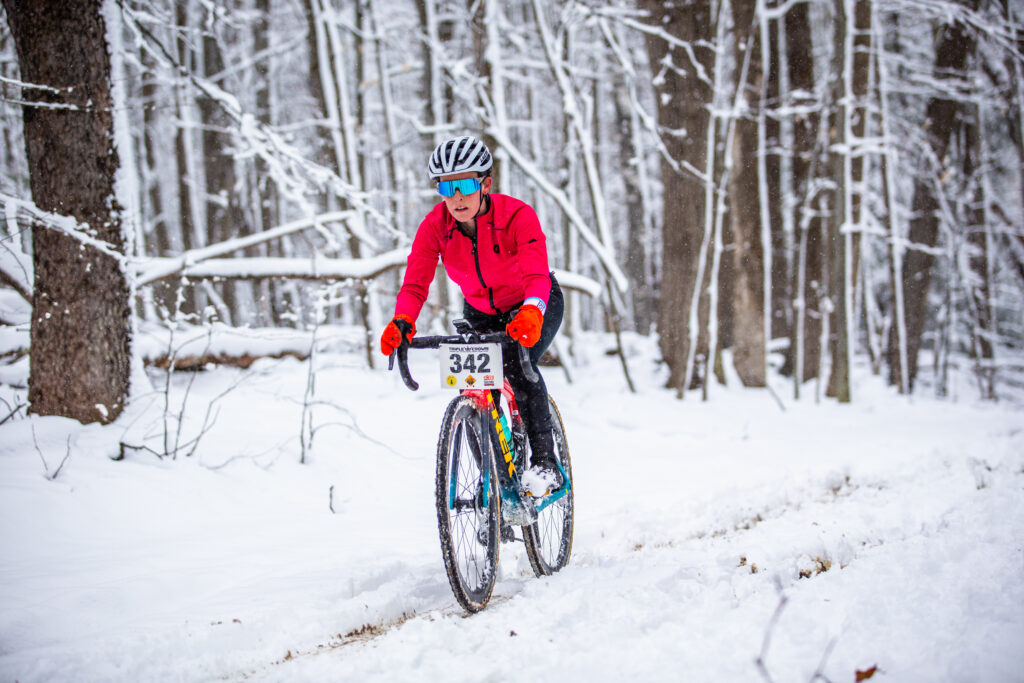 Charlotte Lellman racing through snowy conditions during the Pavement Ends gravel race for the BikeReg | Share Coffee team.