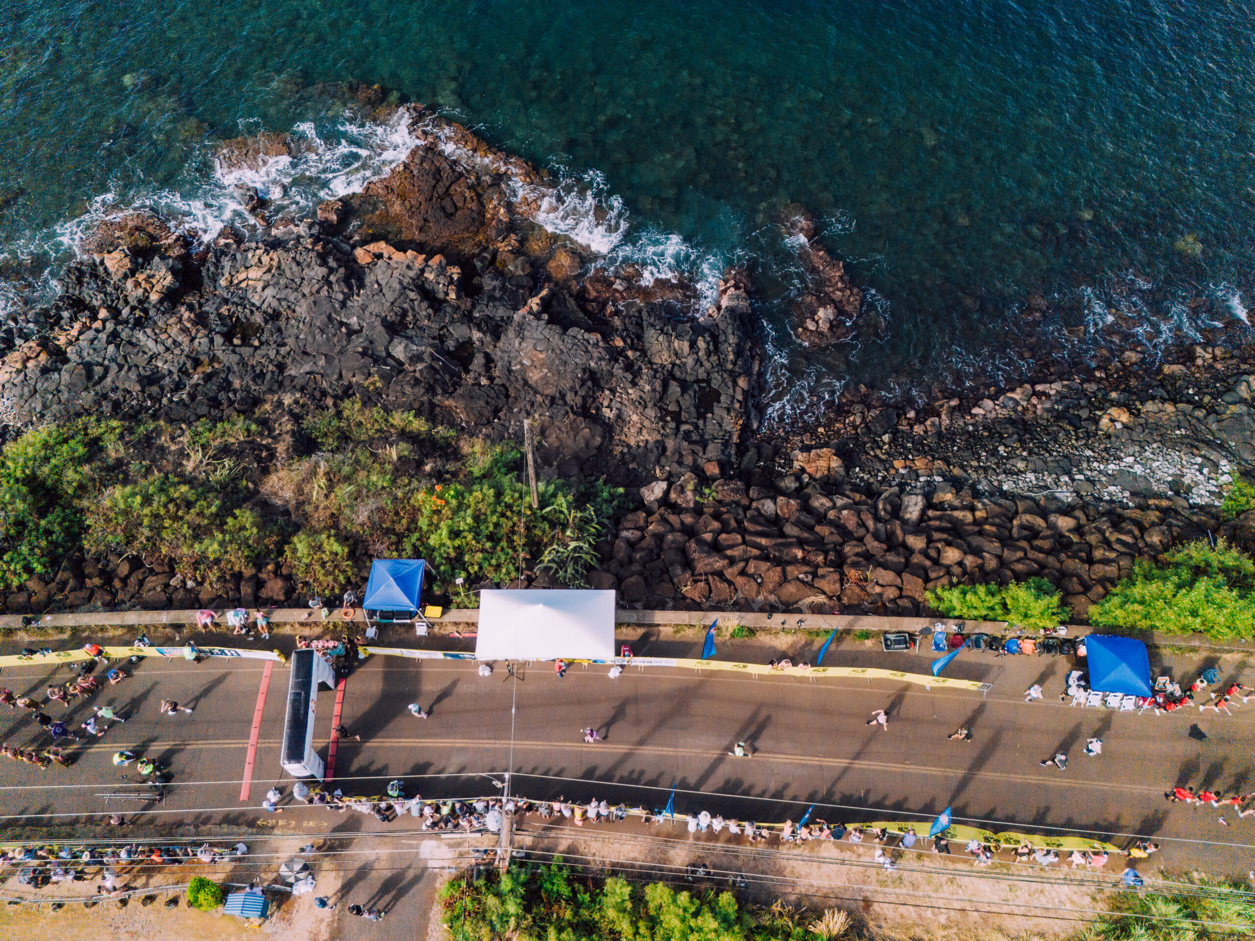 Aerial view of runners crossing the finish line along the ocean at the Kauai Marathon and Half Marathon in Hawaii.
