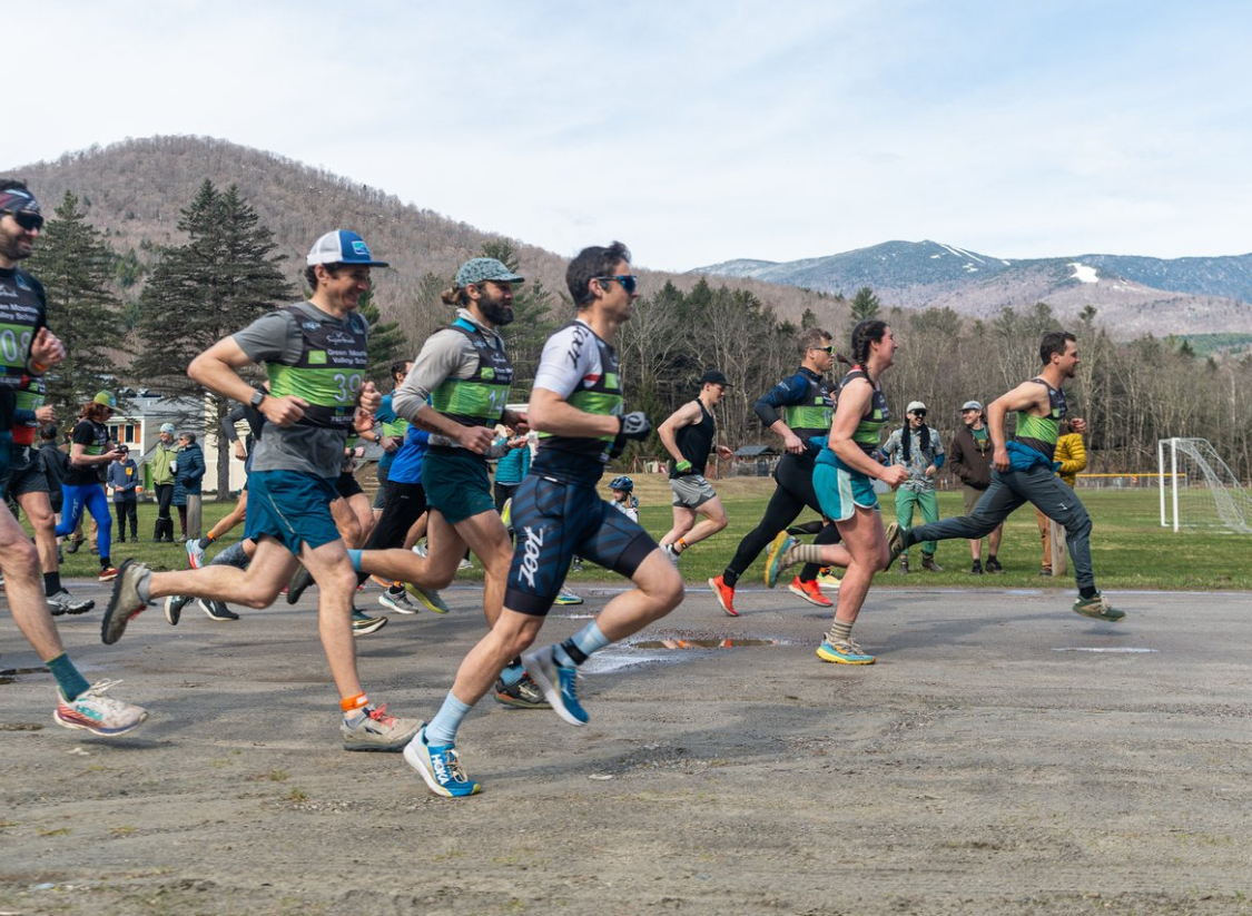 Group of runners at the start of a road race with mountain scenery in the background